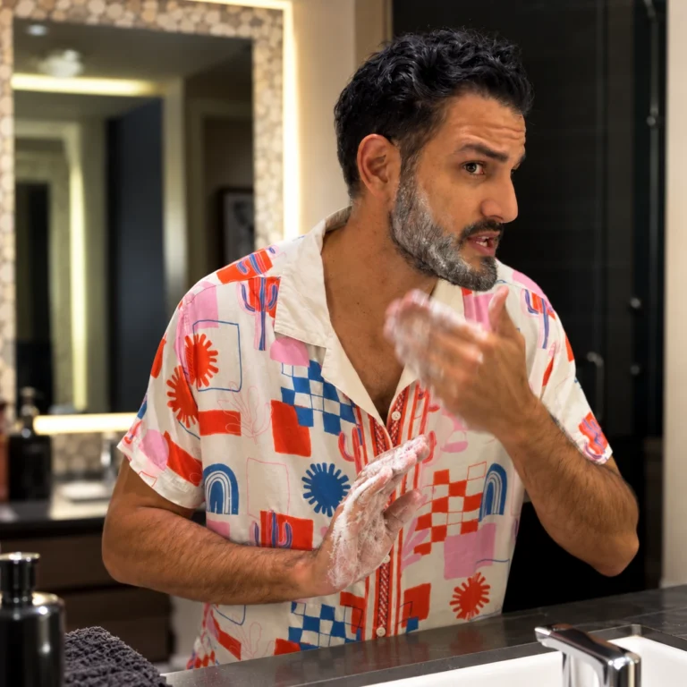 Man washing his beard in a bathroom as part of a beard dandruff care routine